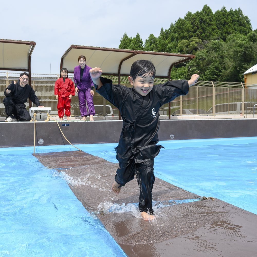 浮橋を走る黒い忍者衣装の子ども