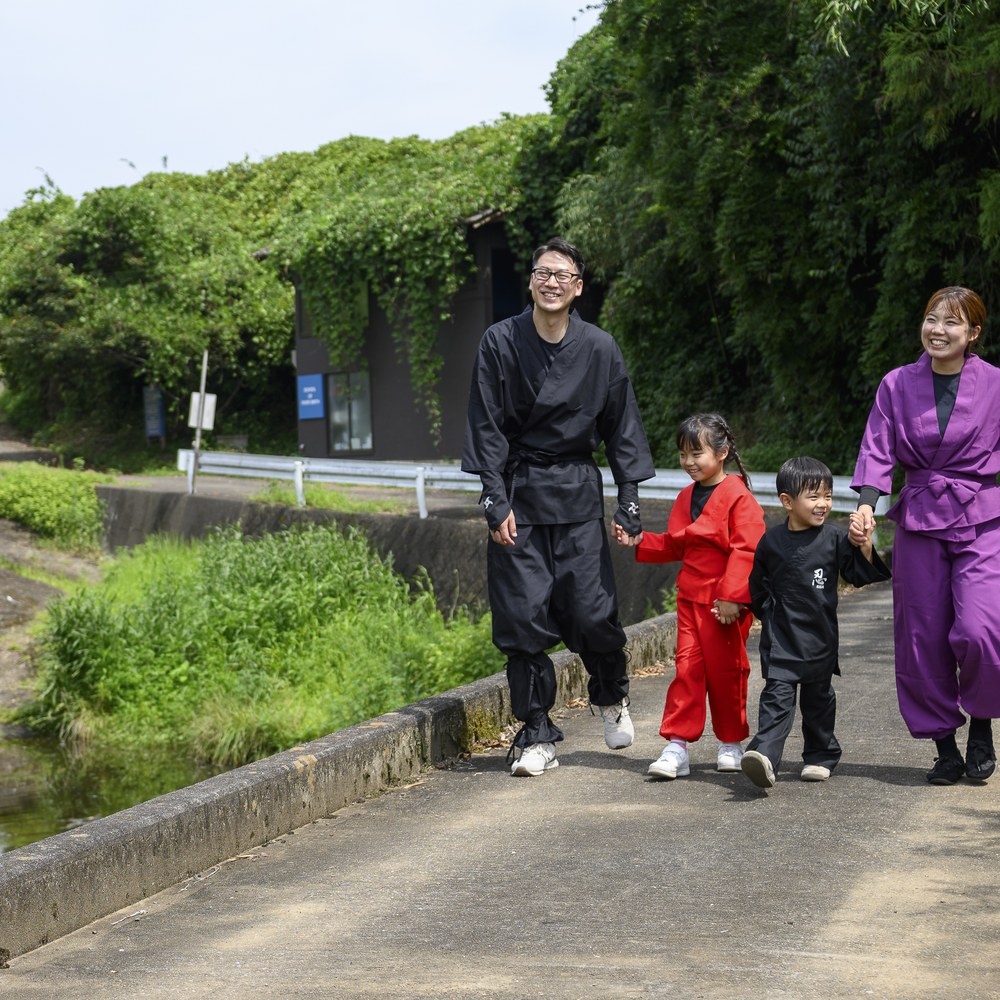 里山を歩く忍者衣装の家族